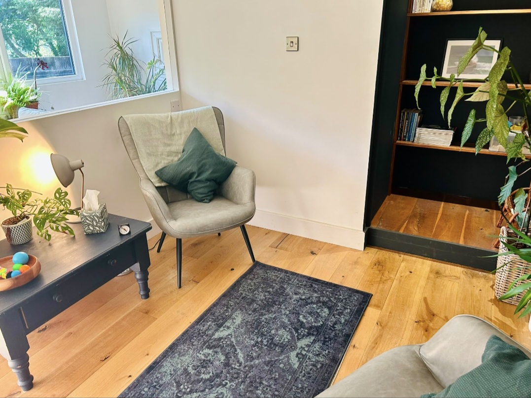 Inside the Penryn studio — a comfortable armchair, rug, lamp and plants in warm natural light
